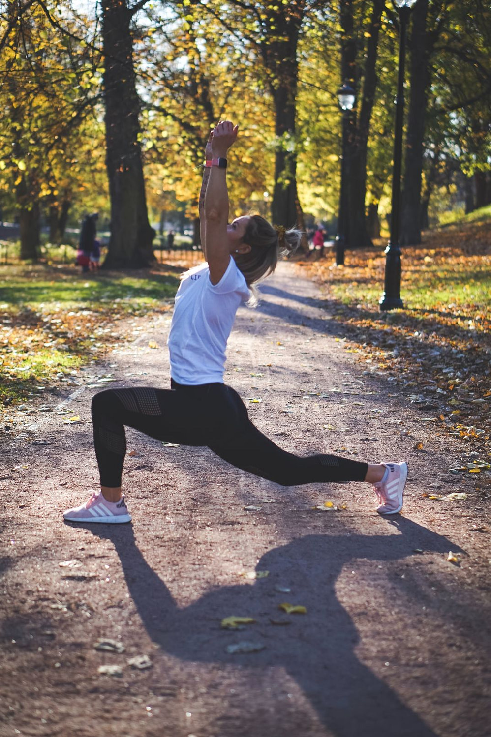 jogger with fitbit stretching on a path in a park